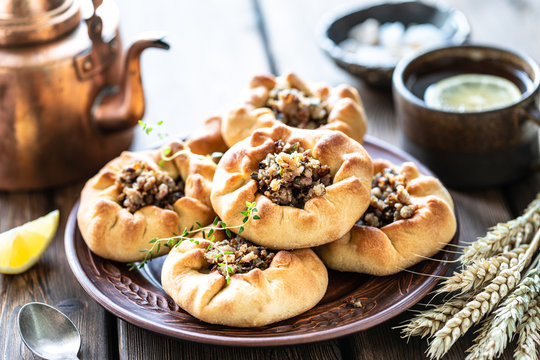 Group of individual pies with meat and potato - vak balish. Tatar traditional pies. Wooden background.