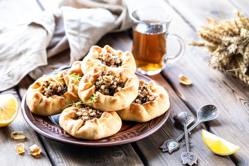 Group of individual pies with meat and potato - vak balish. Tatar traditional pies. Wooden background