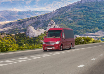 Red minibus moves on a road in the mountains