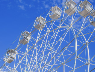 White ferris wheel against the blue sky. Ferris wheel in the park