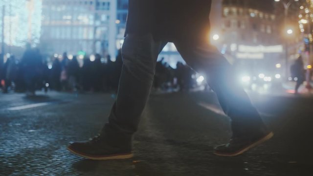 Casually dressed person walking on colorful busy city street at night.Low angle slow motion of a man crossing a vibrant backlit city intersection.Original 10 bit clip.