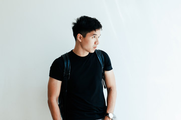 Young handsome asian boy wearing black plain shirt and backpack at day in Sai Gon city, Vietnam - Casual lifestyle of Vietnamese teenager