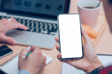 Mockup image blank white screen cell phone.man hand holding texting using mobile on desk at office.background empty space for advertise text.people contact marketing business,technology 