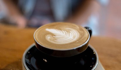 cup of coffee with cream on wooden background