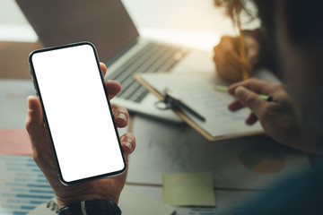 Mockup image blank white screen cell phone.man hand holding texting using mobile on desk at office.background empty space for advertise text.people contact marketing business,technology 