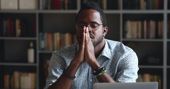 Serious african man praying asking for help or concentrating