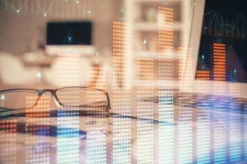 Financial chart hologram with glasses on the table background. Concept of business. Double exposure.