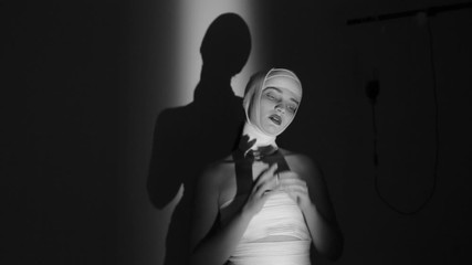 Mad girl with a bandaged head. A girl showing aggression and panic in behavior. Black and white video.