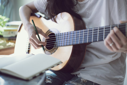 songwriter thinking and writing notes,lyrics in book at studio.man playing live acoustic guitar.concept for musician creative.artist composer in work process.people relaxing time with instrument 