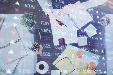 Fototapeta na wymiar Hand taking notes in notepad. Forex chart holograms in front. Concept of research. Double exposure