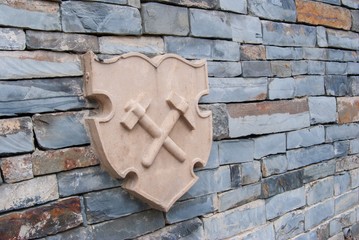 stone blazon with two miner hammers on the wall made from slate bricks