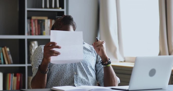 Excited african male student employee read good news in letter
