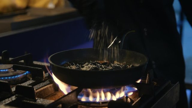 Closeup male chef hands preparing food at fire. Cooker adding grated cheese