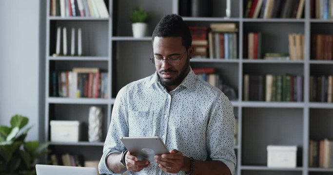Focused african businessman holding using digital tablet in office