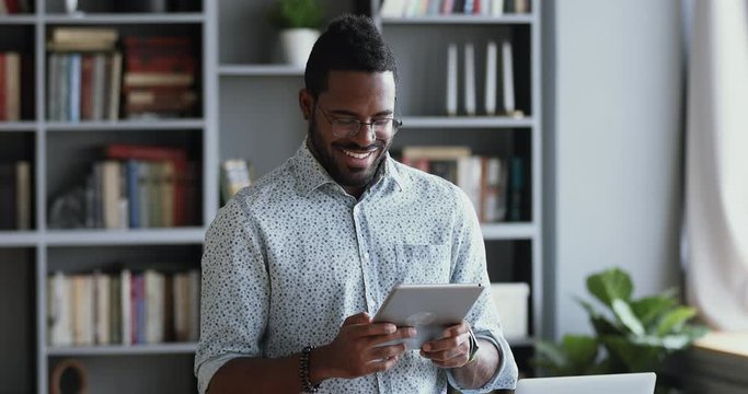 Happy african man professional using digital tablet stand in office
