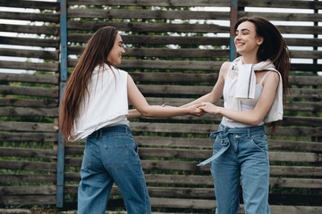 Portrait of Two Young Brunette Twins Sisters Dressed Alike in Jeans and White T-shirt, Best Friends Forever Concept