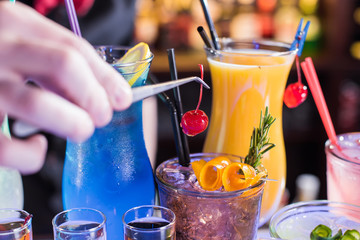 The barman finishes preparing cocktails by putting a cherry
