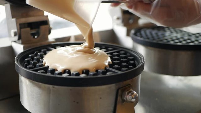 Pouring a dough on waffle iron. Chef step by step preparing Belgian waffles with bananas, strawberries, ice cream, honey and chocolate syrup