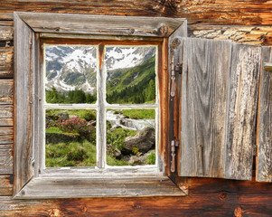 Berglandschaft mit Wildbach und Gletscher gesehen durch ein Holzfenster im Zillertal in Tirol