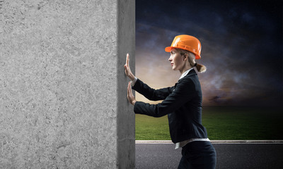 Beautiful woman architect pushing concrete wall