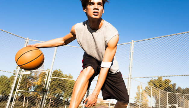 Handsome man playing basketball outside. 