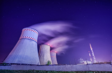 Thermal power plant and cooling towers at night near the city