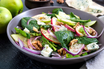 Tasty diet fitness salad with spinach, apples, red onions, blue cheese, nuts. Proper nutrition.