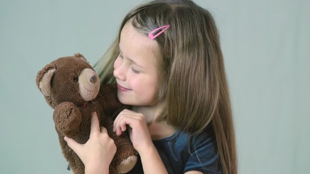 Pretty child girl playing with her teddy bear toy.