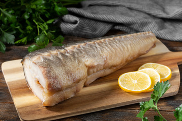  Hot smoked sturgeon on a wooden Board on a brown wooden table.