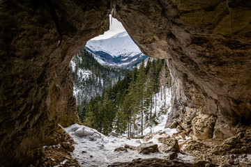 Hole (Pawlikowski's Window) in the Mylna Cave (False Cave) in the Koscieliska Valley in the Western Tatras, with a view of the winter landscape of the mountains, Poland.