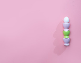 Easter eggs in a stand, trendy pink background, hard light, minimalistic concept.