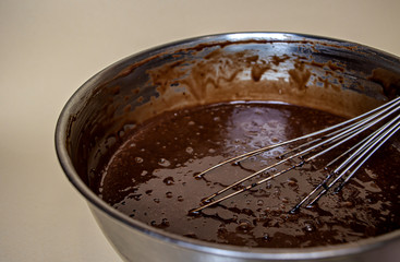 chocolate dough in a steel bowl and steel whisk close up