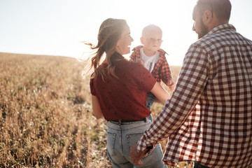 Happy Young Family Mom and Dad with Their Little Son Enjoying Summer Weekend Picnic Outside the City in the Field at Sunny Day Sunset, Vacation Time Concept