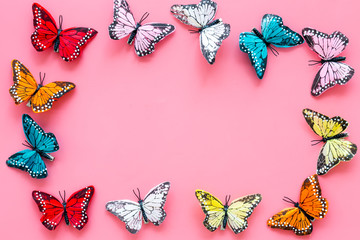 Multicolored tropical butterflies on pink background top-down frame copy space