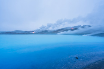 Geothermal powerplant at the blue lagoon in Jarabodin/Myvatn in Iceland during blue hour. Long exposure shot of steam smoke and azure blue lake. Traveling concept.