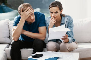 Stressed married couple looking frustrated, having no money to pay off their debts, managing family...