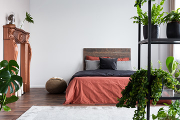 Copy space on empty white wall of rustic bedroom interior with king size bed with orange bedding...