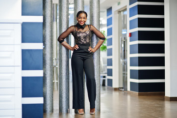 Charming african american woman in black formal wear posing at restaurant.
