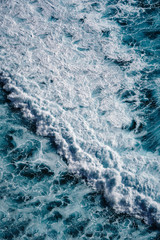 Aerial view to seething waves with foam. Waves of the sea meet each other during high tide and low tide.