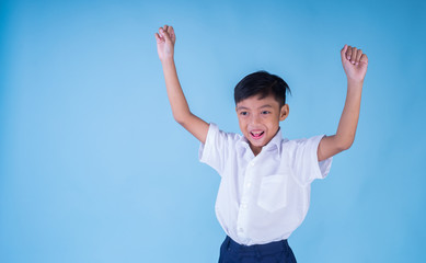 An ecstatic Asian school boy wearing white shirt and blue pants over blue background smiling cheerfully. Back to school concept. Isolated. Landscape orientation. 