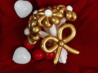 Bouquet of flowers from gold and white balloons on red velvet.