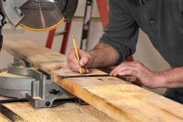 closeup of carpenter marking line on wooded board with pencil and wooden square during remodel