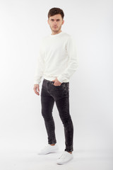 Young european man in white sweater and black pants posing on white background. Isolated.