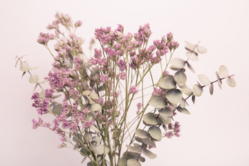 Ramo decorativo con eucalipto y flores moradas sobre fondo blanco. © Eva
