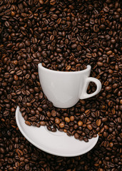 white coffee cup lies in roasted coffee beans of the highest standard