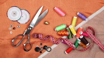 Set of tailoring tools and accessories on orange fabric