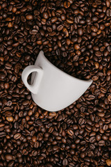 white coffee cup lies in roasted coffee beans of the highest standard