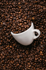 white coffee cup lies in roasted coffee beans of the highest standard