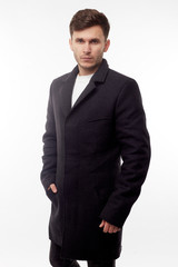 Fototapeta premium Handsome man in black winter coat, black jeans and boots isolated on white background.