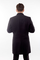 Handsome man in black winter coat, black jeans and boots isolated on white background.